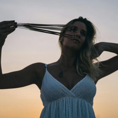 A woman holding incense sticks in a peaceful sunset setting, embracing calmness and spirituality.