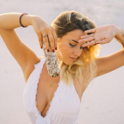 A serene woman practicing sage smudging outdoors for calming and purification.